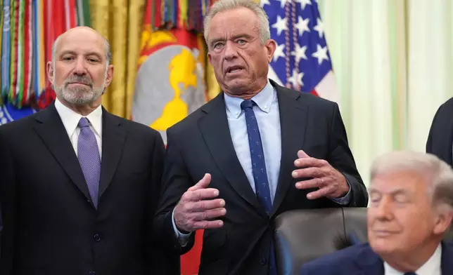 Health and Human Services Secretary Robert F. Kennedy Jr. speaks as President Donald Trump and Commerce Secretary Howard Lutnick listen during an event on health care affordability in the Oval Office at the White House, Thursday, April 23, 2026, in Washington. (AP Photo/Mark Schiefelbein)