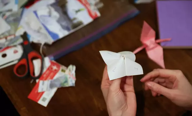 Guests play an origami game from the 90s during a weekly phone-free gathering at the home of organizer Dan Fox in the Brooklyn borough of New York, Wednesday, March 25, 2026. (AP Photo/Heather Khalifa)