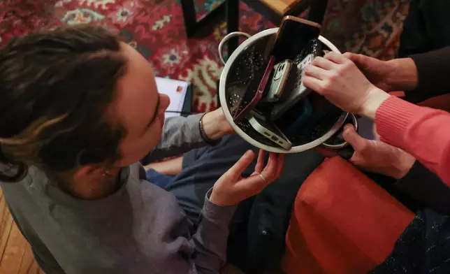 Guests collect their smartphones at the end of a weekly phone-free gathering at the home of organizer Dan Fox in the Brooklyn borough of New York, Wednesday, March 25, 2026. (AP Photo/Heather Khalifa)