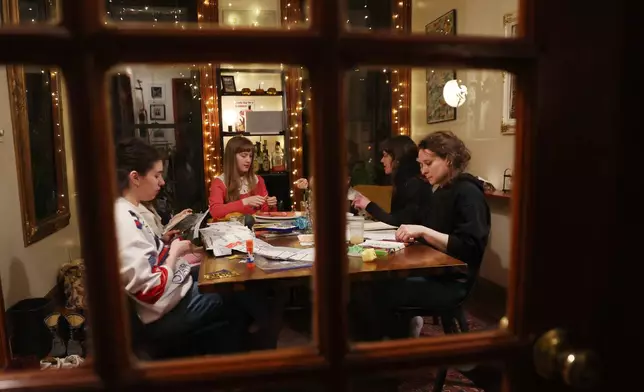 Guests journal and knit together during a weekly phone-free gathering at the home of organizer Dan Fox in the Brooklyn borough of New York, Wednesday, March 25, 2026. (AP Photo/Heather Khalifa)