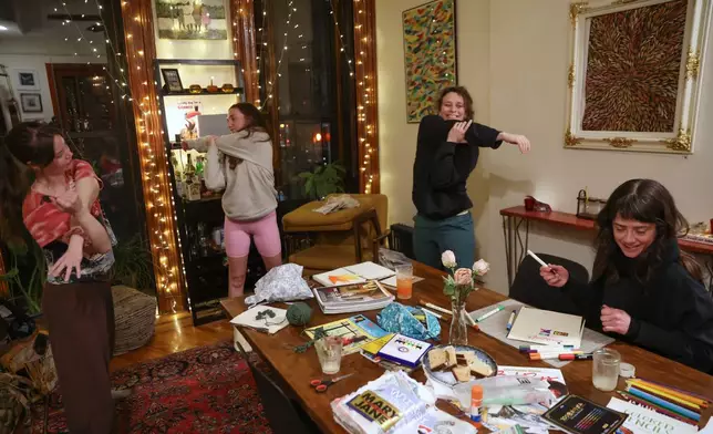 Guests stretch during a weekly phone-free gathering at the home of organizer Dan Fox in the Brooklyn borough of New York, Wednesday, March 25, 2026. (AP Photo/Heather Khalifa)