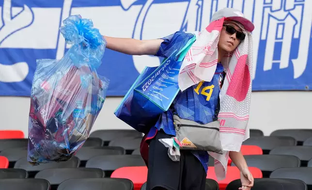 FILE - Japan's supporters clean their seats after losing the World Cup, group E soccer match between Japan and Costa Rica, at the Ahmad Bin Ali Stadium in Al Rayyan , Qatar, on Nov. 27, 2022. (AP Photo/Eugene Hoshiko, File)
