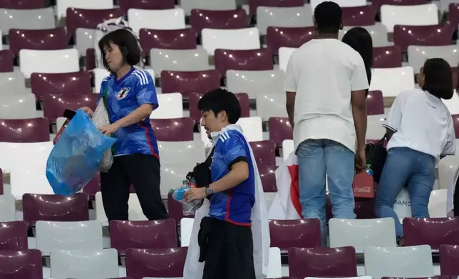 FILE - Japan supporters clean the stands at the end of the World Cup group E soccer match between Germany and Japan, at the Khalifa International Stadium in Doha, Qatar, Wednesday, Nov. 23, 2022. (AP Photo/Eugene Hoshiko, File)