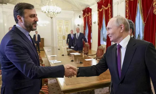 Russian President Vladimir Putin, right, shakes hands with Iranian Deputy Foreign Minister Kazem Gharibabadi, at the Boris Yeltsin Presidential Library, in St. Petersburg, Russia, Monday, April 27, 2026. (Gavriil Grigorov, Sputnik, Kremlin Pool Photo via AP)