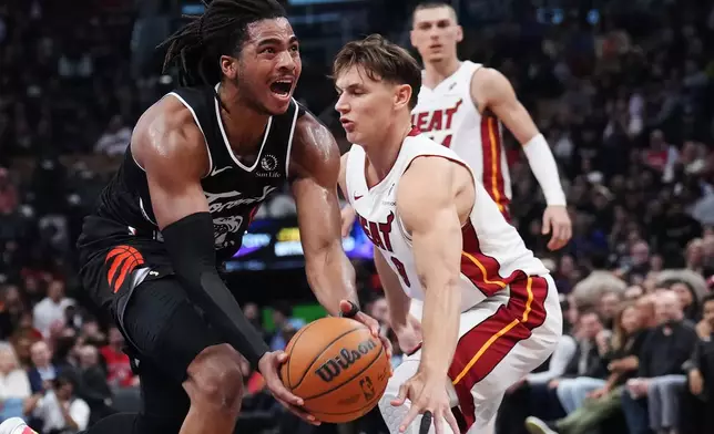 Toronto Raptors' Collin Murray-Boyles (left) drives past Miami Heat's Pelle Larsson (9) during the first period of an NHL game in Ottawa, Thursday, April 9, 2026. (Adrian Wyld/The Canadian Press via AP)