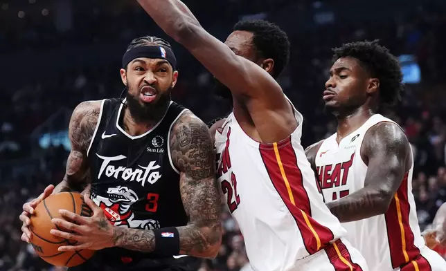 Toronto Raptors' Brandon Ingram (3) drives as Miami Heat's Andrew Wiggins (22) defends during first-half NBA basketball game action in Toronto, Thursday, April 9, 2026. (Nathan Denette/The Canadian Press via AP)