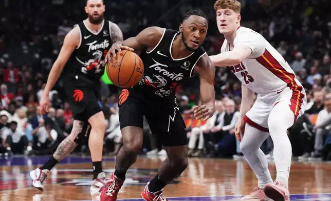 Toronto Raptors' Immanuel Quickley (5) drives past Miami Heat's Kasparas Jakucionis (25) during the first period of an NHL game in Ottawa, Thursday, April 9, 2026. (Adrian Wyld/The Canadian Press via AP)