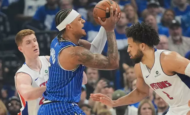 Orlando Magic forward Paolo Banchero, center, goes to the basket between Detroit Pistons guard Kevin Huerter, left, and guard Cade Cunningham during the first half in Game 4 of a first-round NBA basketball playoff series, Monday, April 27, 2026, in Orlando, Fla. (AP Photo/John Raoux)
