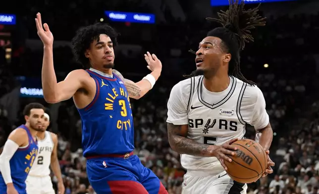 San Antonio Spurs guard Stephon Castle (5) drives against Denver Nuggets guard Julian Strawther during the first half of an NBA basketball game, Sunday, April 12, 2026, in San Antonio. (AP Photo/Darren Abate)