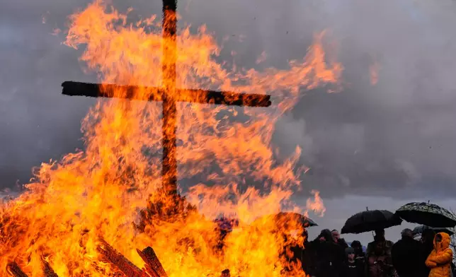 People attend a traditional Easter fire, a traditional bonfire lit symbolizing the resurrection of Jesus Christ, on a mine dump of the last German coal mine, in Bottrop, Germany, Sunday, April 5, 2026. (AP Photo/Martin Meissner)