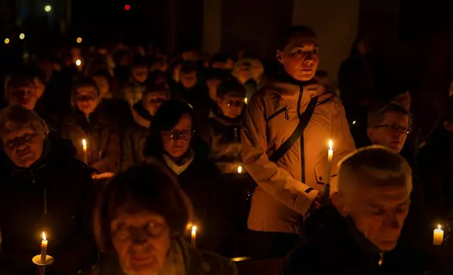 Worshippers hold candles during the Easter vigil Mass in the Cathedral Basilica of Vilnius, Lithuania, late Saturday, April 4, 2026. (AP Photo/Mindaugas Kulbis)