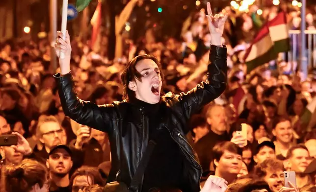 FILE - A man waves a Hungarian flag as he celebrates in the streets after the announcement of partial results of the Hungarian parliamentary elections in Budapest, Hungary, April 12, 2026. (AP Photo/Denes Erdos, File)