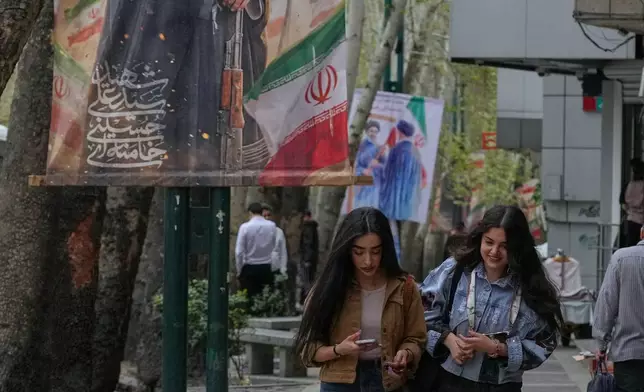 FILE - Women walk past a banner depicting the late Iranian Supreme Leader Ayatollah Ali Khamenei, who was killed in the U.S. and Israel strikes on Feb. 28, in northern Tehran, Iran, April 12, 2026. (AP Photo/Vahid Salemi, File)