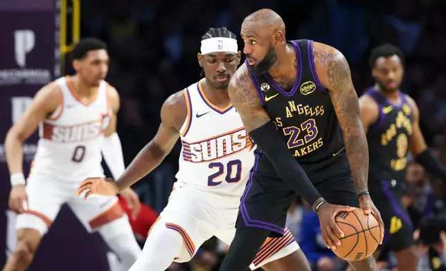 Los Angeles Lakers forward LeBron James (23) holds the ball against Phoenix Suns forward Rasheer Fleming (20) as Suns forward Ryan Dunn, back left, and Lakers guard Bronny James, back right, look on during the first half of an NBA basketball game, Friday, April 10, 2026, in Los Angeles. (AP Photo/Jessie Alcheh)