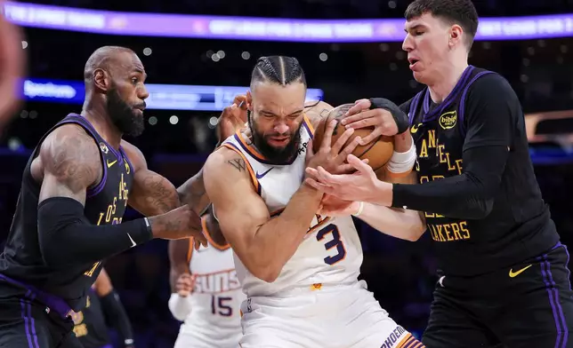 Phoenix Suns forward Dillon Brooks, center, Los Angeles Lakers forward LeBron James, left, and Lakers forward Jake LaRavia, right, battle for the ball during the first half of an NBA basketball game, Friday, April 10, 2026, in Los Angeles. (AP Photo/Jessie Alcheh)