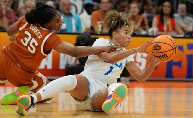 Texas forward Madison Booker (35) and UCLA guard Kiki Rice (1) scramble for the ball during the first half of a women's NCAA college basketball tournament semifinal game at the Final Four, Friday, April 3, 2026, in Phoenix. (AP Photo/Ross D. Franklin)