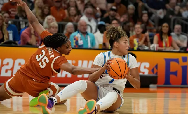 Texas forward Madison Booker (35) and UCLA guard Kiki Rice (1) scramble for the ball during the first half of a women's NCAA college basketball tournament semifinal game at the Final Four, Friday, April 3, 2026, in Phoenix. (AP Photo/Ross D. Franklin)