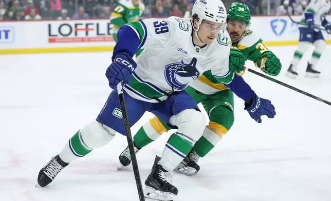 Vancouver Canucks center Ty Mueller (39) skates with the puck ahead of Minnesota Wild right wing Mats Zuccarello (36) during the first period of an NHL hockey game Thursday, April 2, 2026, in St. Paul, Minn. (AP Photo/Matt Krohn)