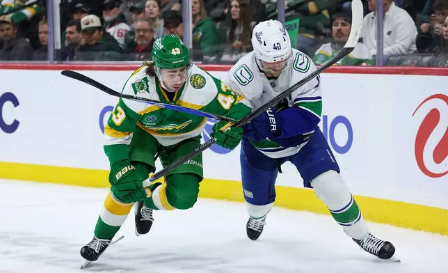 Minnesota Wild defenseman Quinn Hughes, left, and Vancouver Canucks center Elias Pettersson (40) compete for the puck during the second period of an NHL hockey game Thursday, April 2, 2026, in St. Paul, Minn. (AP Photo/Matt Krohn)