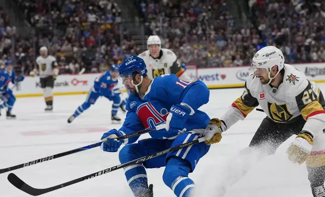 Colorado Avalanche center Nicolas Roy, left, struggles to control the puck as Vegas Golden Knights defenseman Shea Theodore covers in the first period of an NHL hockey game Saturday, April 11, 2026, in Denver. (AP Photo/David Zalubowski)