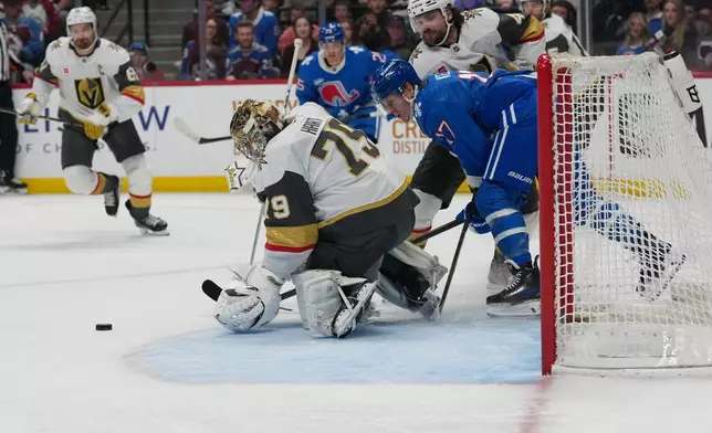 Colorado Avalanche center Parker Kelly, front right, fights past Vegas Golden Knights defenseman Rasmus Andersson, back right, as goaltender Carter Hart stops a shot in the first period of an NHL hockey game Saturday, April 11, 2026, in Denver. (AP Photo/David Zalubowski)