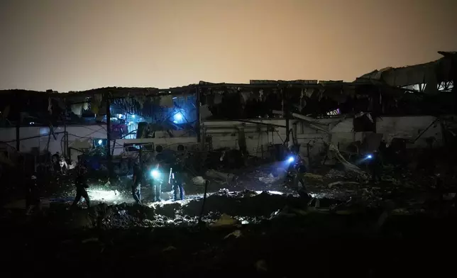 Israeli security forces and rescue teams inspect a site struck by an Iranian missile in Petah Tikva, Israel,Thursday, April 2, 2026. (AP Photo/Ohad Zwigenberg)