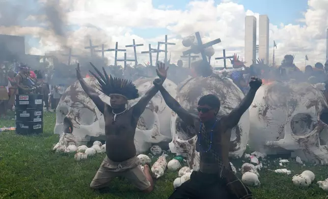 Indigenous protesters set fire to skull sculptures representing lawmakers to protest Congress during the annual "Acampamento Terra Livre," or Free Land Encampment, Brazil's largest annual Indigenous mobilization that focuses on land rights and environmental protection, in Brasilia, Brazil, Tuesday, April 7, 2026. (AP Photo/Eraldo Peres)