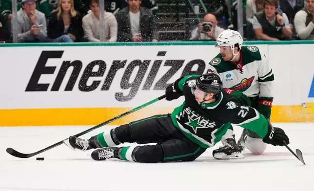 Dallas Stars left wing Jason Robertson (21) falls attempting to take a shot as Minnesota Wild's Brock Faber (7) defends in the third period of Game 2 of a first-round NHL Stanley Cup playoffs hockey series Monday, April 20, 2026, in Dallas. (AP Photo/Tony Gutierrez)un