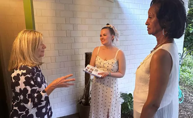 Laura Kajfez, left, speaks with Casey Clowes, center and Sandra Kennedy, candidates for the Salt River Project governing board, outside her home in Tempe, Ariz., on Wednesday, April 1, 2026. (AP Photo/Jonathan J. Cooper)