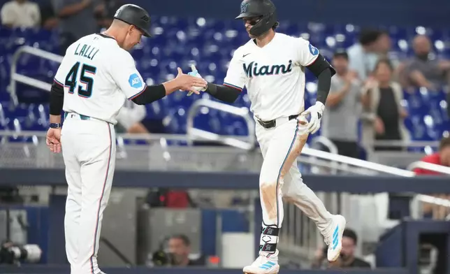 Miami Marlins' Connor Norby, right, is met by third base coach Blake Lalli (45) after hitting solo home run during the seventh inning of a baseball game against the Cincinnati Reds, Wednesday, April 8, 2026, in Miami. (AP Photo/Lynne Sladky)