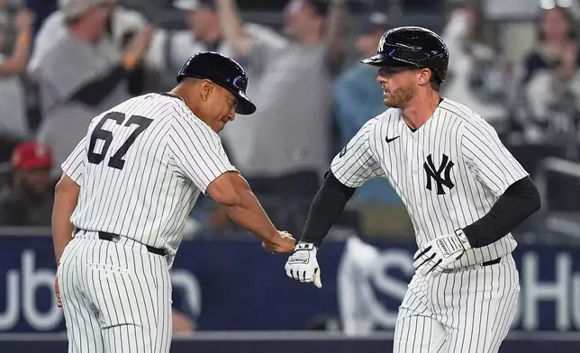 New York Yankees' Ryan McMahon, right, celebrates with third base coach Luis Rojas as he runs the bases after hitting a two-run home run during the eighth inning of a baseball game against the Kansas City Royals Friday, April 17, 2026, in New York. (AP Photo/Frank Franklin II)