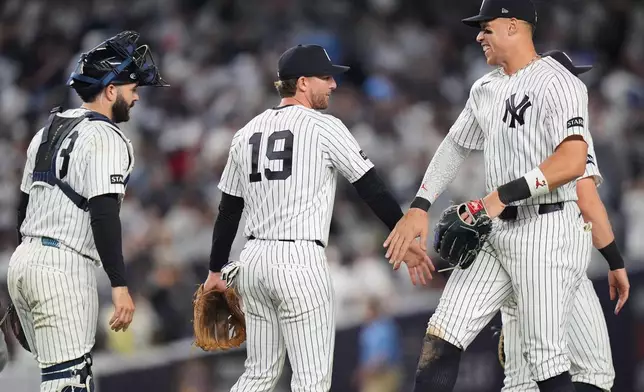 New York Yankees' Aaron Judge, right, celebrates with Ryan McMahon, center, and Austin Wells after a baseball game against the Kansas City Royals Friday, April 17, 2026, in New York. (AP Photo/Frank Franklin II)