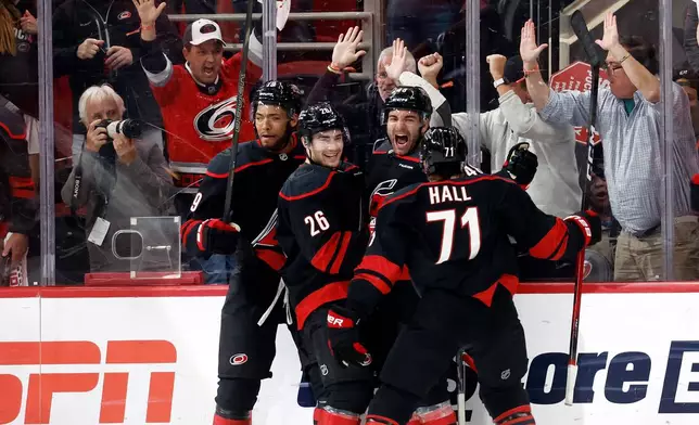 Carolina Hurricanes' Jordan Martinook, second from right, celebrates after his winning overtime goal with Sean Walker (26), Taylor Hall (71) and K'andre Miller (19) following the second overtime of Game 2 of an NHL hockey Stanley Cup first-round playoff series against the Ottawa Senators in Raleigh, N.C., Monday, April 20, 2026. (AP Photo/Karl DeBlaker)