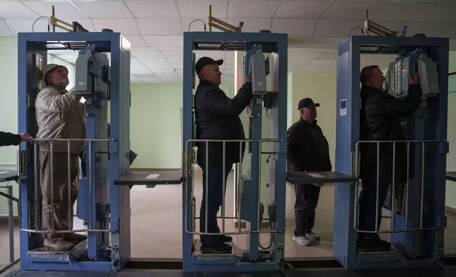 Workers who were sent to clean up contamination from the 1986 Chernobyl nuclear power plant accident, pass through a radiation inspection point, Tuesday, April 21, 2026, at the plant in Chernobyl, Ukraine. (AP Photo/Evgeniy Maloletka)
