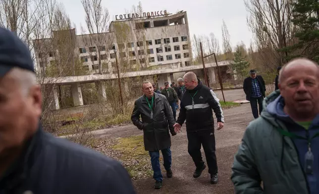 Stanislav Tolumnyi, 65, left, and Mykola Chudak, 66, walk with fellow workers who helped clean up contamination from the 1986 Chernobyl nuclear disaster, in the nearby abandoned town of Prypiat, Ukraine, Tuesday, April 21, 2026, ahead of the 40th anniversary of the accident. (AP Photo/Evgeniy Maloletka)