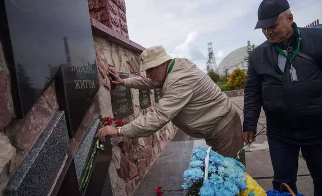 Workers sent to help clean up the effects of the 1986 Chernobyl nuclear power plant accident, place flowers at a monument in front of the facility, Tuesday, April 21, 2026, in Chernobyl, Ukraine. (AP Photo/Evgeniy Maloletka)