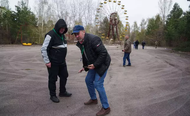 Workers sent to clean up contamination from the Chernobyl nuclear power plant accident walk in the nearby abandoned town of Prypiat, Ukraine, during a return visit to the region, Tuesday, April 21, 2026. (AP Photo/Evgeniy Maloletka)