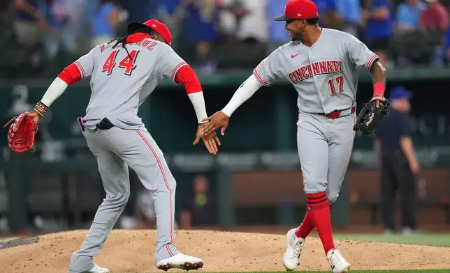 Cincinnati Reds shortstop Elly de la Cruz (44) and center fielder Dane Myers (17) react after their team defeated the Texas Rangers 5-3 during the Rangers' home-opener baseball game Friday, April 3, 2026, in Arlington, Texas. (AP Photo/Julio Cortez)