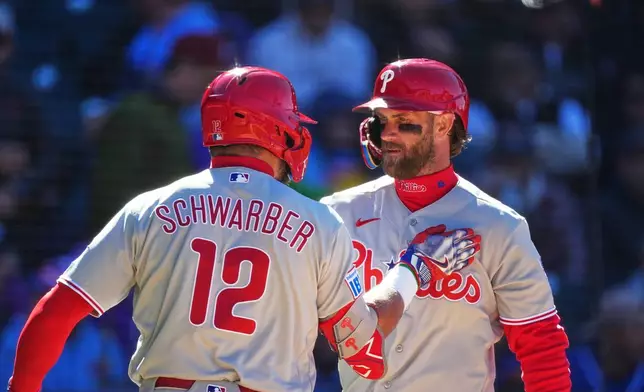 Philadelphia Phillies' Bryce Harper, right, congratulates Kyle Schwarber after his solo home run off Colorado Rockies relief pitcher Valente Bellozo in the fifth inning of a baseball game Friday, April 3, 2026, in Denver. (AP Photo/David Zalubowski)