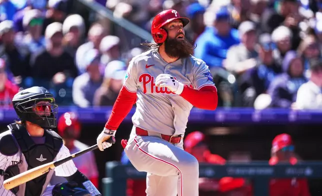 Philadelphia Phillies' Brandon Marsh, right, follows the flight of his three-run home run off Colorado Rockies starting pitcher Michael Lorenzen in the first inning of a baseball game Friday, April 3, 2026, in Denver. (AP Photo/David Zalubowski)