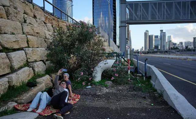 A man takes a selfie while taking cover with three others along a highway as air raid sirens warn of an incoming Iranian missile strike in Tel Aviv, Israel, Tuesday, April 7, 2026. (AP Photo/Ohad Zwigenberg)