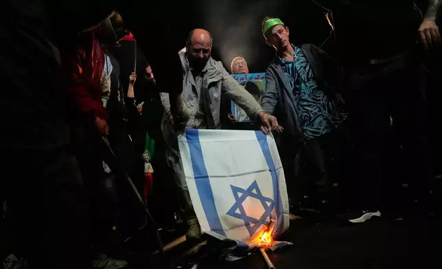 Iranian pro-government demonstrators burn an Israeli flag during a gathering after the announcement of a two-week ceasefire in the war with the Unites States and Israel, at the Enqelab-e-Eslami, or Islamic Revolution, Square in Tehran, Iran, Wednesday, April 8, 2026. (AP Photo/Vahid Salemi)