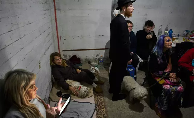 People take cover in a bomb shelter as air raid sirens warn of incoming Iranian missile strikes in Ramat Gan, Israel, Tuesday, April 7, 2026. (AP Photo/Oded Balilty)
