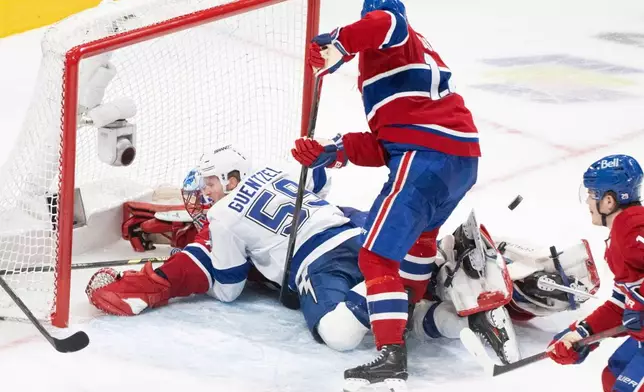 Tampa Bay Lightning's Jake Guentzel (59) crashes into Montreal Canadiens goaltender Jakub Dobes, bottom left, as Canadiens' Nick Suzuki, center, looks for the puck during the second period of Game 4 in a first-round NHL hockey Stanley Cup playoff series in Montreal, Sunday, April 26, 2026. (Christinne Muschi/The Canadian Press via AP)