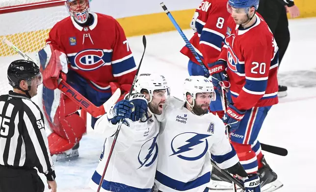 Tampa Bay Lightning's Brandon Hagel (38) celebrates with teammate Nikita Kucherov (86) after scoring against Montreal Canadiens goaltender Jakub Dobes (75) as Canadiens' Juraj Slafkovsky (20) looks on during third period NHL playoff hockey action in Montreal, Sunday, April 26, 2026. (Graham Hughes/The Canadian Press via AP)