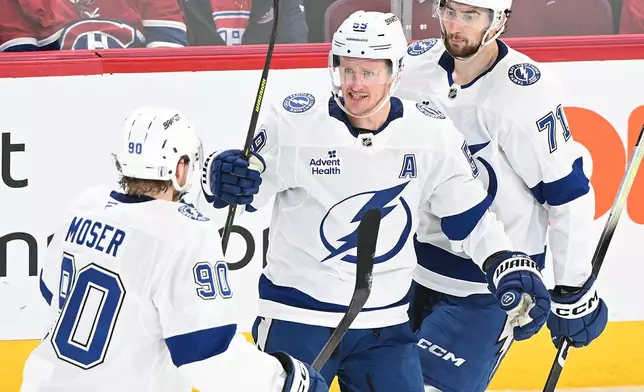 Tampa Bay Lightning's Jake Guentzel (59) celebrates with teammates J.J. Moser (90) and Anthony Cirelli (71) after scoring against the Montreal Canadiens during the second period of Game 4 in a first-round NHL hockey Stanley Cup playoff series in Montreal, Sunday, April 26, 2026. (Graham Hughes/The Canadian Press via AP)