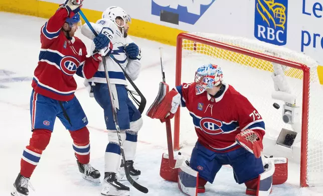 Tampa Bay Lightning's Brandon Hagel (38) scores past Montreal Canadiens goaltender Jakub Dobes (75) and Mike Matheson (8) during the third period of an NHL playoff hockey game, in Montreal, Sunday, April 26, 2026. (Christinne Muschi/The Canadian Press via AP)