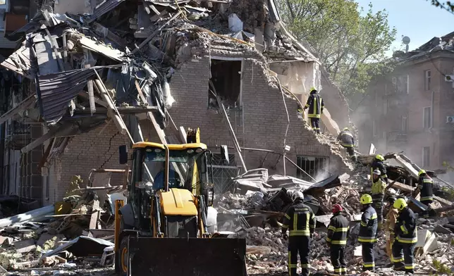 Rescue workers clear the rubble of a residential building destroyed by a Russian strike on Dnipro, Ukraine, Saturday, April 25, 2026. (AP Photo/Mykola Synelnykov)