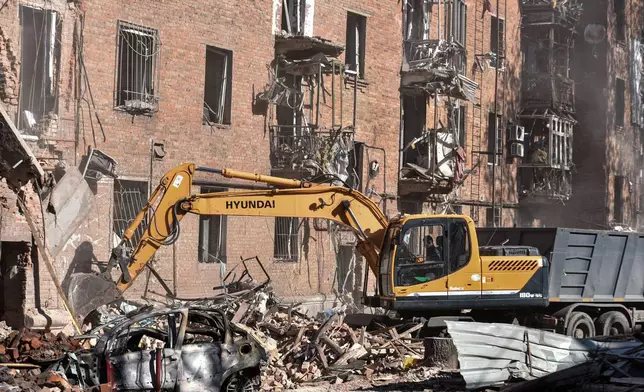 En excavator clears the rubble of a residential building destroyed by a Russian strike on Dnipro, Ukraine, Saturday, April 25, 2026. (AP Photo/Mykola Synelnykov)