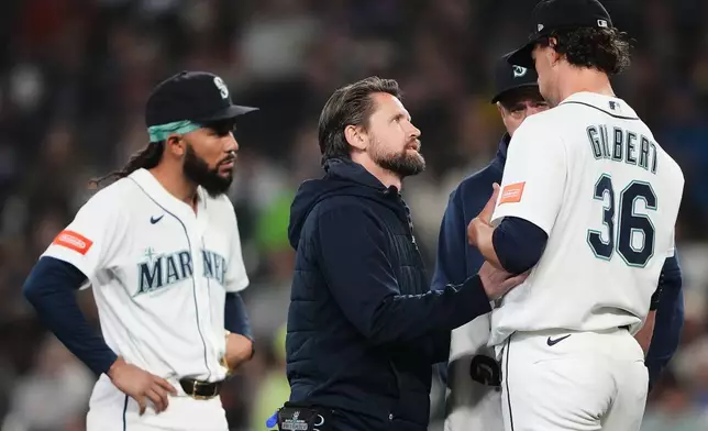 Seattle Mariners head athletic trainer Kyle Torgerson checks on starting pitcher Logan Gilbert after Athletics' Carlos Cortes hit a line drive into his jersey during the first inning of a baseball game, Wednesday, April 22, 2026, in Seattle. (AP Photo/Lindsey Wasson)